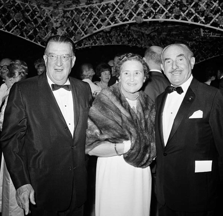 Walter O’Malley with his wife Kay are greeted by Warner Bros. co-founder Jack Warner (right) at the star-studded Hollywood premiere of 'My Fair Lady' on October 28, 1964.